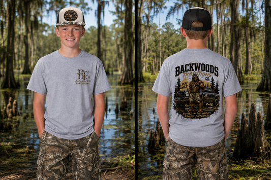A split view of a young man wearing a light gray t-shirt in a swamp forest. The left side shows the front of the shirt with a small brown 'Backwoods' logo, and the right side shows the back of the shirt with a large graphic of a Bigfoot hunting scene and 'BACKWOODS FISHING' text.